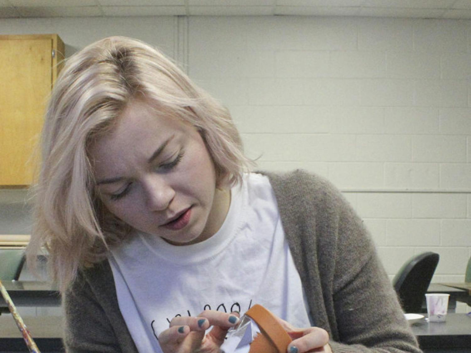 Marisa Panzarella, a 22-year-old UF advertising junior, glues CD shards to a gardening pot at a C.R.E.A.T.E. club meeting on Nov. 18, 2015, in McCarty A. Panzarella said she didn’t know what she wanted to make, but she showed up to have fun. Since Thanksgiving is next week, the event also included a potluck of apple pie, honey straws, cookies and macaroni and cheese.