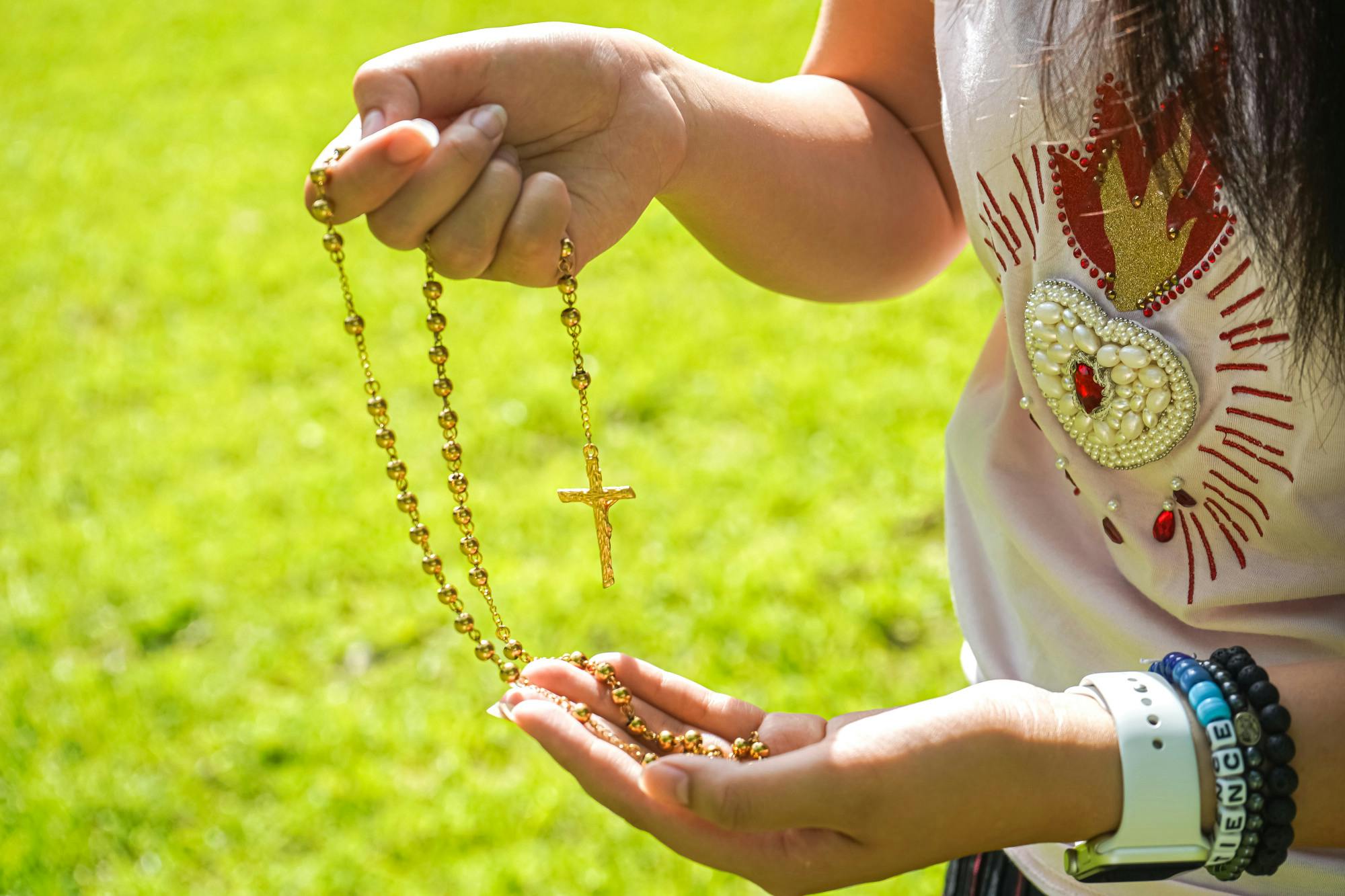 Victoria Nguyen prays the rosary as she walks by the UF Honors Village.
