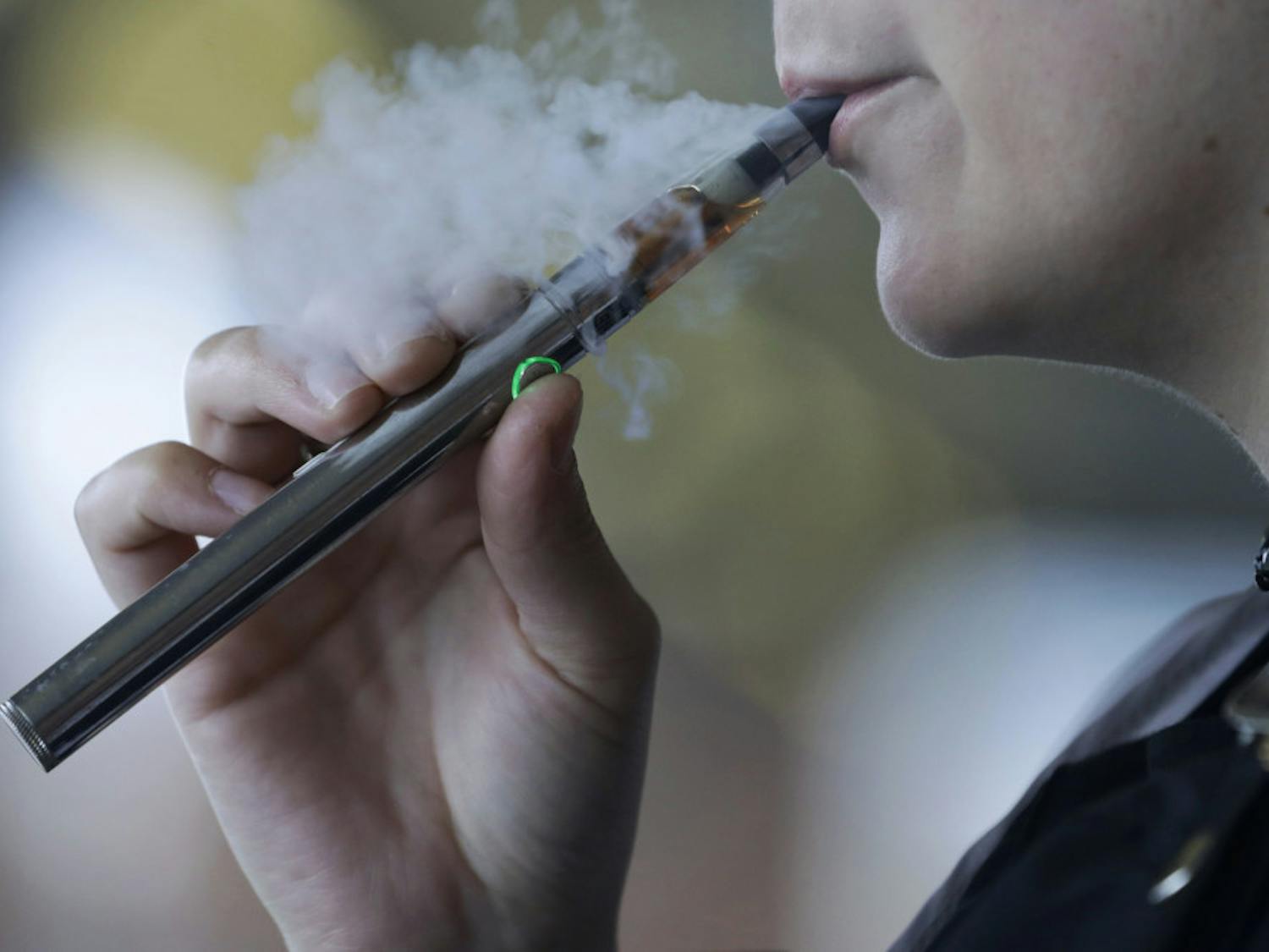 FILE - In this Friday, Oct. 4, 2019, file photo, a woman using an electronic cigarette exhales in Mayfield Heights, Ohio. A Michigan judge is blocking the state's two-week-old ban on flavored e-cigarettes. Court of Claims Judge Cynthia Stephens issued a preliminary injunction Tuesday, Oct. 15, 2019. She says Michigan Gov. Gretchen Whitmer's administration's delay in implementing the ban undercut its position that emergency rules were needed. (AP Photo/Tony Dejak, File)