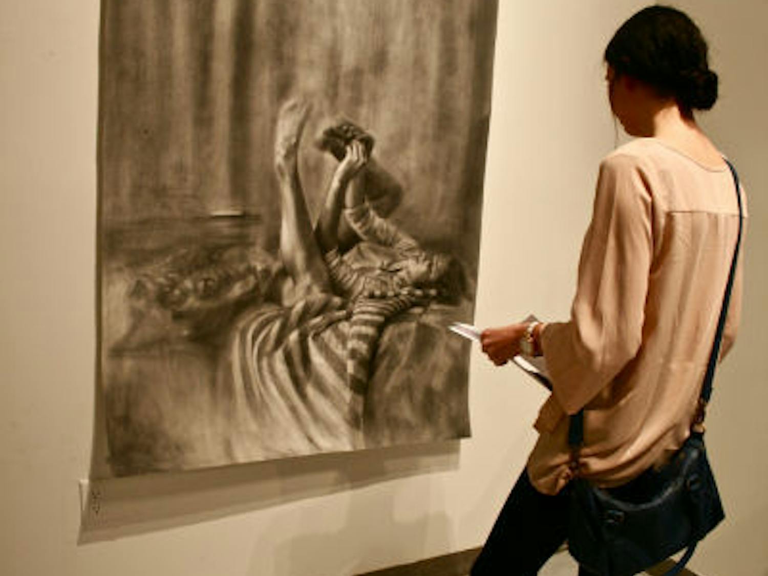 Amara Harnish, a 21-year-old UF English junior, admires the work of senior drawing student Kelly O’Brien at “TEASER: An Advanced Drawing Group Exhibition.” The event showcases drawing seniors’ works and will run through Thursday at the WARPhaus Gallery on Fourth Avenue.