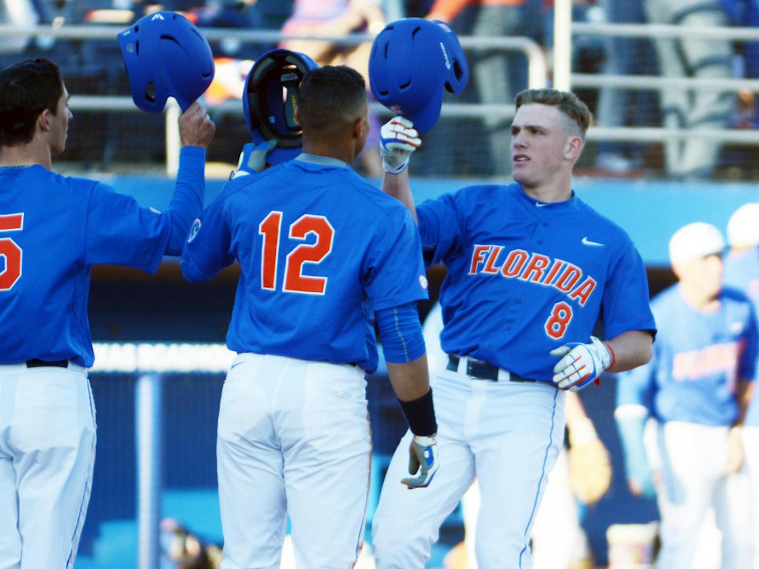 Harrison Bader (8) celebrates with Dalton Guthrie (5) and Richie Martin (12) after hitting a home run during Florida's 22-3 win against Rhode Island on Saturday at McKethan Stadium.