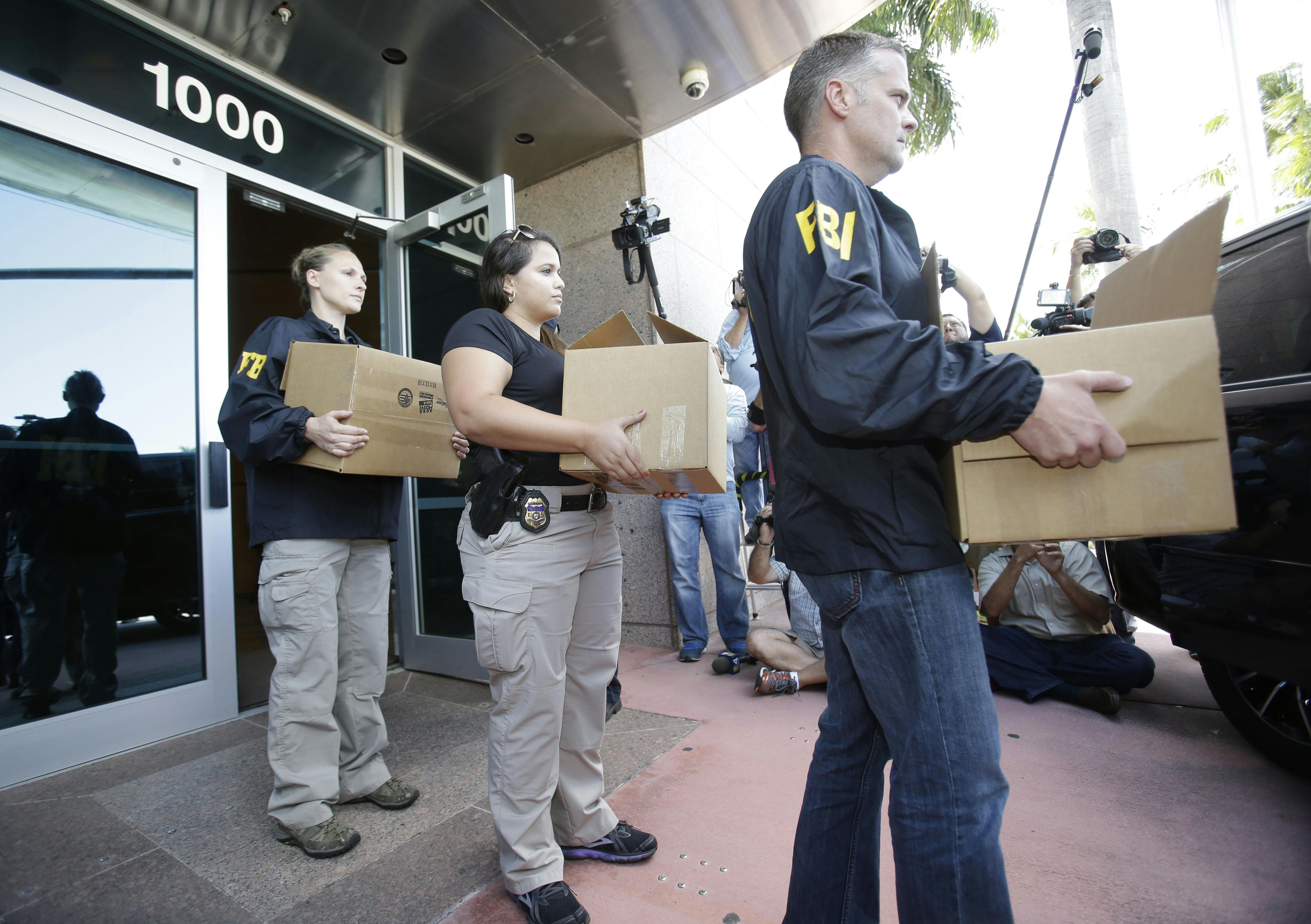 Federal agents carry out boxes of evidence taken from the headquarters of the Confederation of North, Central America and Caribbean Association Football (CONCACAF,) Wednesday, May 27, 2015, in Miami Beach, Fla. Swiss prosecutors opened criminal proceedings into FIFA's awarding of the 2018 and 2022 World Cups, only hours after seven soccer officials were arrested Wednesday pending extradition to the U.S. in a separate probe of "rampant, systemic, and deep-rooted" corruption.