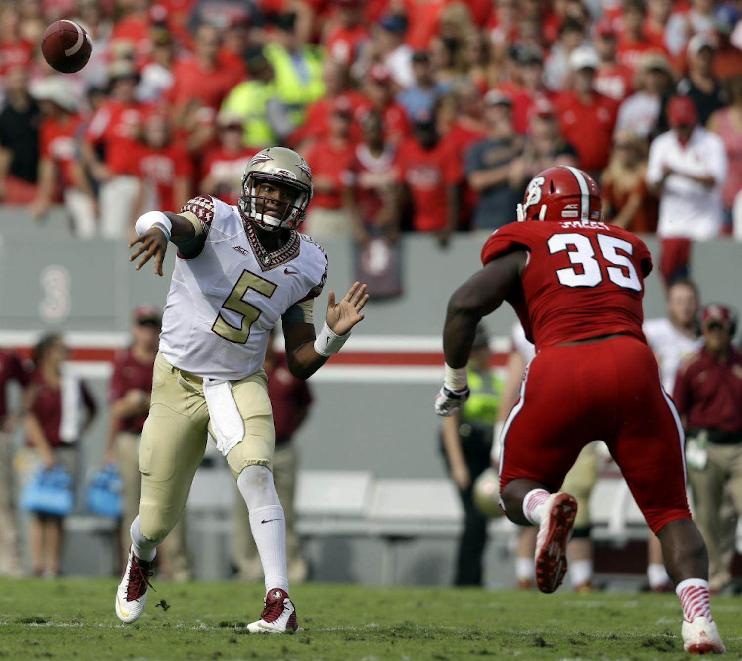 Florida State quarterback Jameis Winston (5) throws a pass as North Carolina State's Kentavius Street (35) rushes during the first half of an NCAA college football game in Raleigh, N.C., Saturday, Sept. 27, 2014.