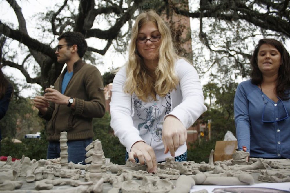 <p>Janelle Pornovetz, 22, reorganizes clay bones on Turlington Plaza on Wednesday afternoon. Read a story about the One Million Bones project at alligator.org.</p>