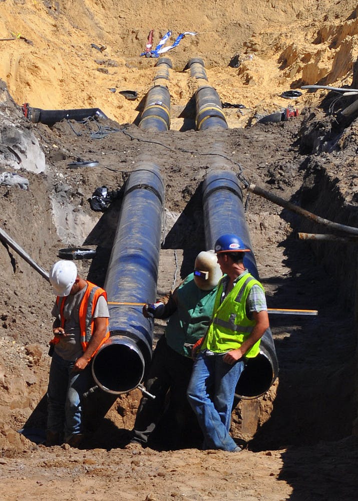 Three construction workers wait for dirt to be cleared at the site of the future Innovation Square. The roads will increase the partnership between downtown and UF.