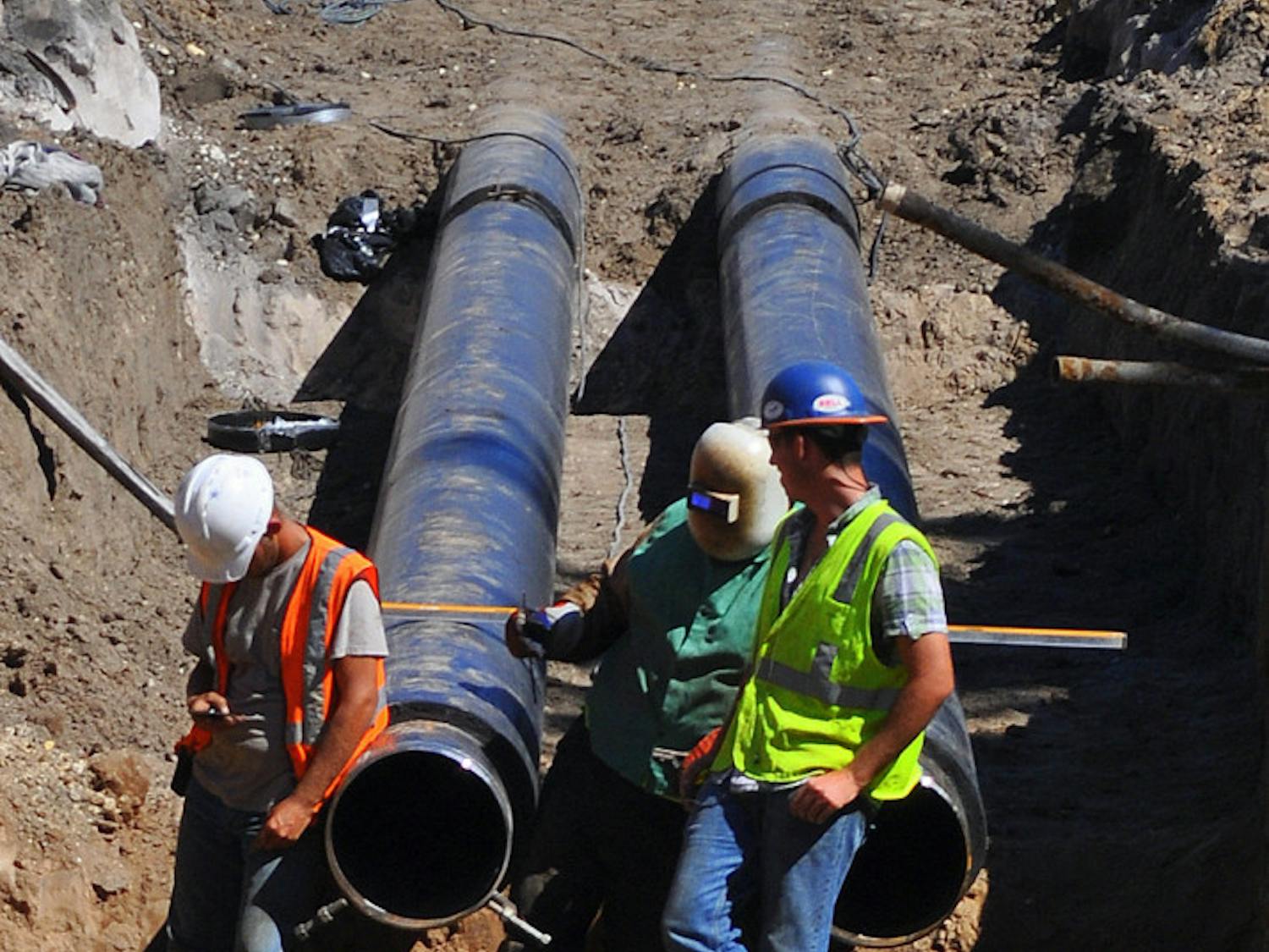 Three construction workers wait for dirt to be cleared at the site of the future Innovation Square. The roads will increase the partnership between downtown and UF.