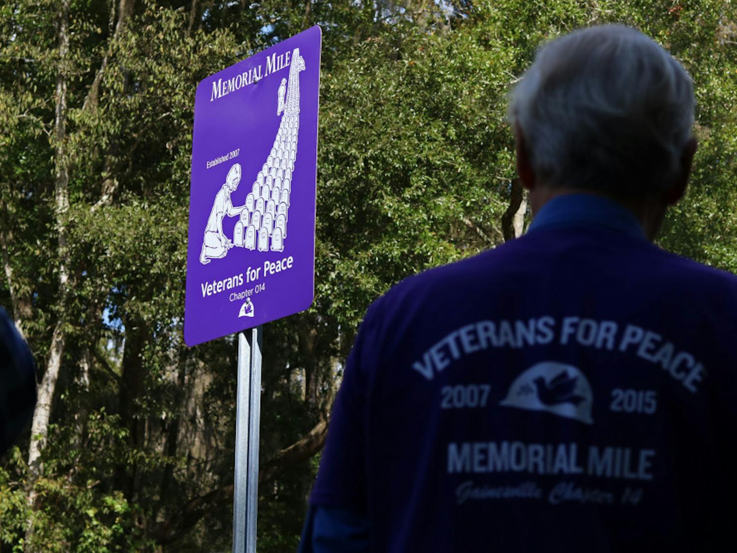 Members of the organization Veterans for Peace look at the newly unveiled Memorial Mile marker on NW 8th Avenue Monday. During Memorial Day weekend each year, the organization places tombstones marking the names of every U.S. service member who has died in Iraq and Afghanistan.