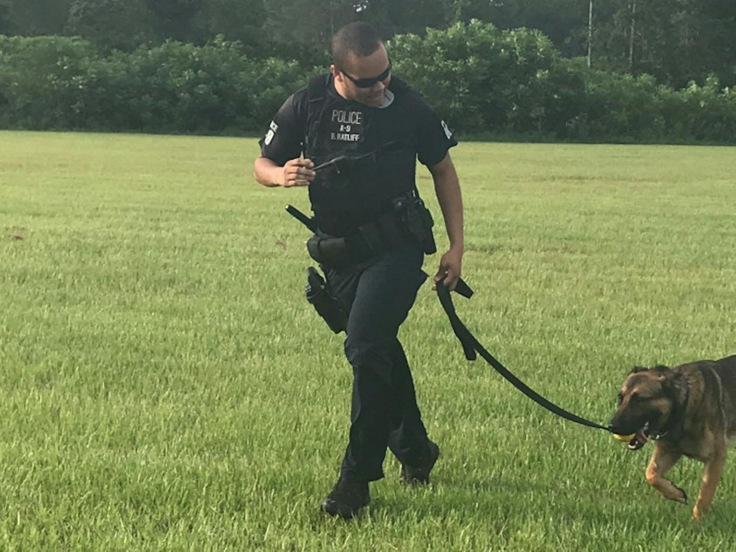 Officer Ed Ratliff and his dog, Ace, run off the field after doing apprehension training. Another officer wore a sleeve for Ace to safely bite down on his forearm.
