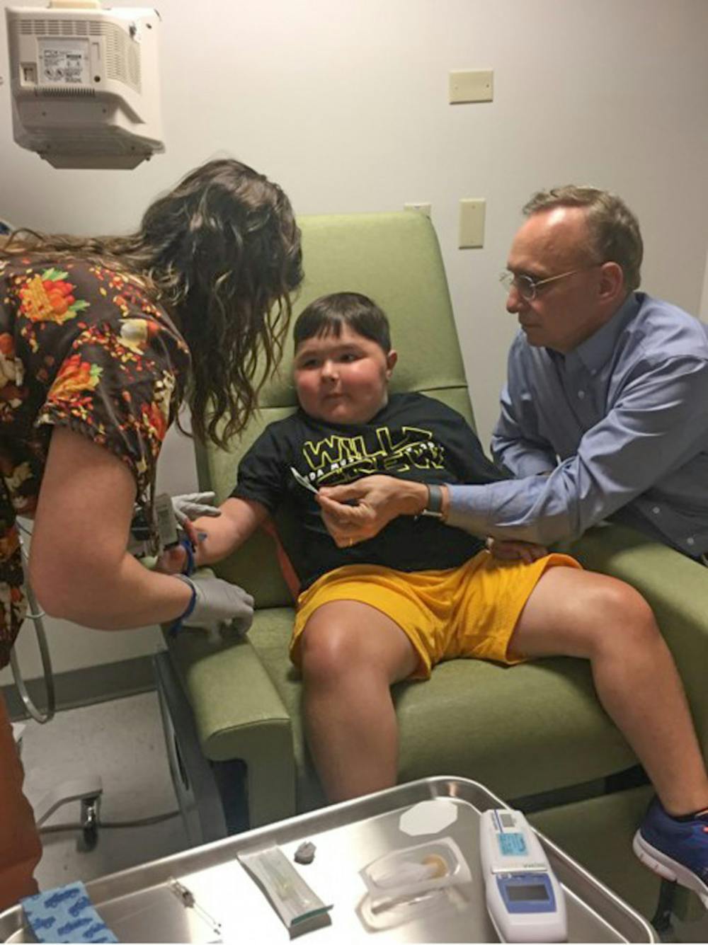 <p dir="ltr">A UF Health Shands Hospital nurse tends to 9-year-old Will Barkoskie’s IV while Dr. Barry Byrne, a UF College of Medicine professor, looks on. Diagnosed with Duchenne muscular dystrophy, Barkoskie is receiving groundbreaking treatment at Shands.</p>