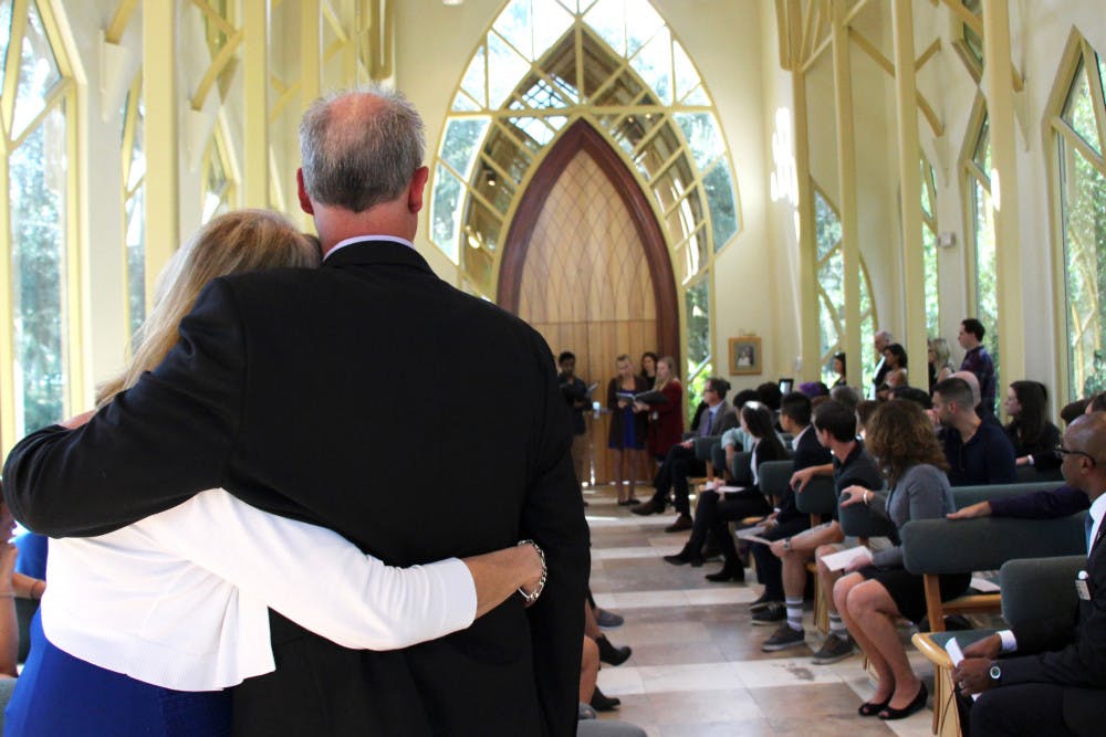 Ian Burns’ parents, Monique and Rick, embrace one another as a group of Ian’s friends perform the song “At the River” by Aaron Copland inside the Baughman Center on Thursday afternoon.