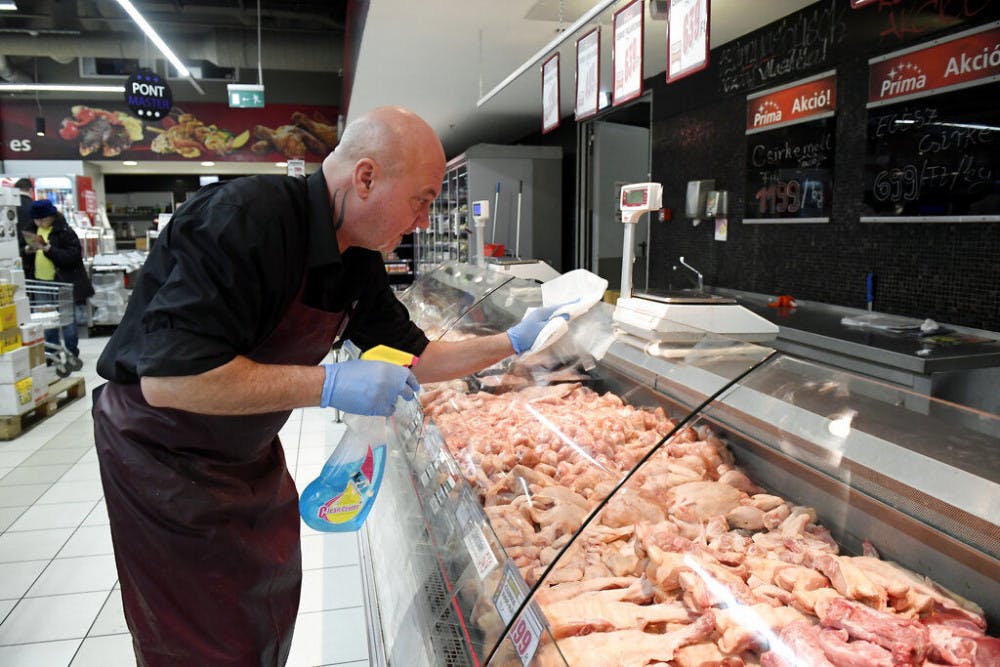 <p>An employee disinfects the glass cover of a butcher counter to prevent the spread of the novel coronavirus in a food store in Budapest, Hungary, Wednesday, March 11, 2020. For most people, the new coronavirus causes only mild or moderate symptoms, such as fever and cough. For some, especially older adults and people with existing health problems, it can cause more severe illness, including pneumonia. (Tamas Kovacs/MTI via AP)</p>