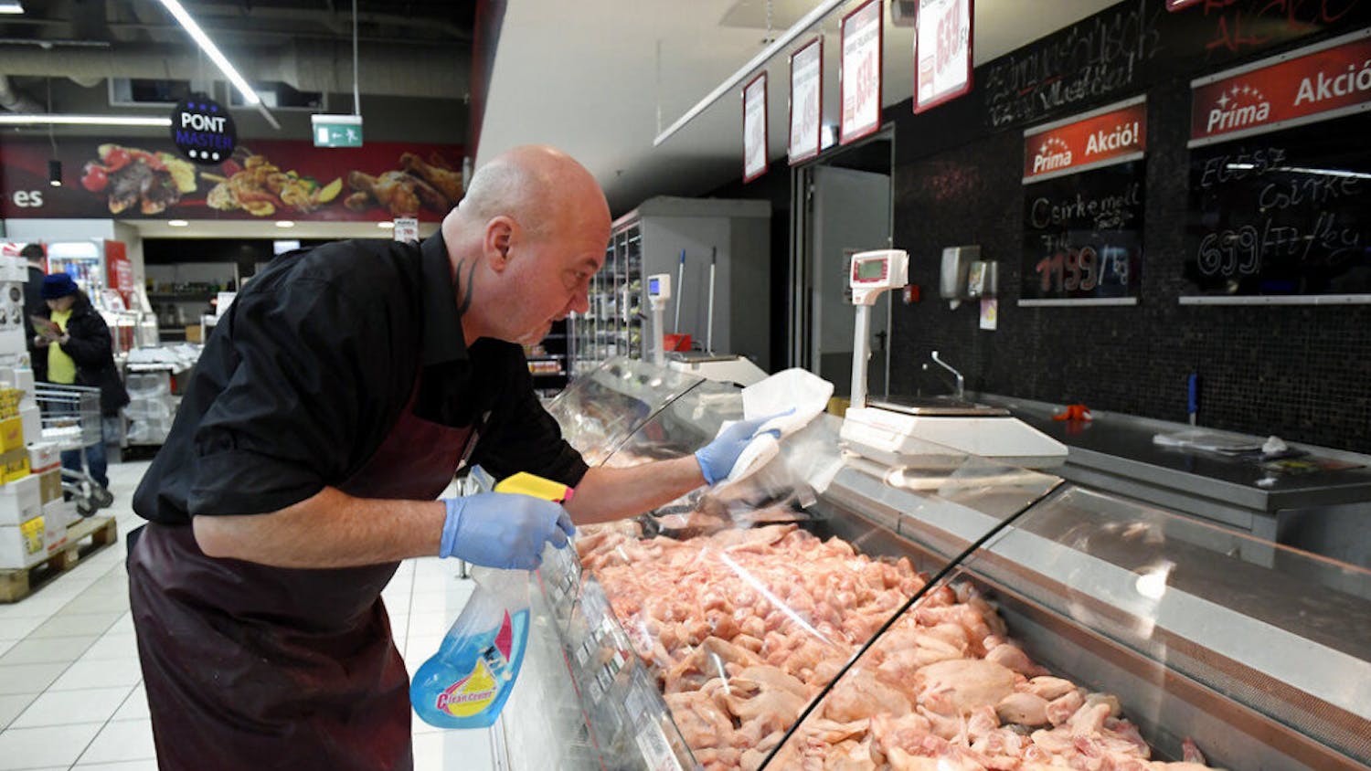 An employee disinfects the glass cover of a butcher counter to prevent the spread of the novel coronavirus in a food store in Budapest, Hungary, Wednesday, March 11, 2020. For most people, the new coronavirus causes only mild or moderate symptoms, such as fever and cough. For some, especially older adults and people with existing health problems, it can cause more severe illness, including pneumonia. (Tamas Kovacs/MTI via AP)