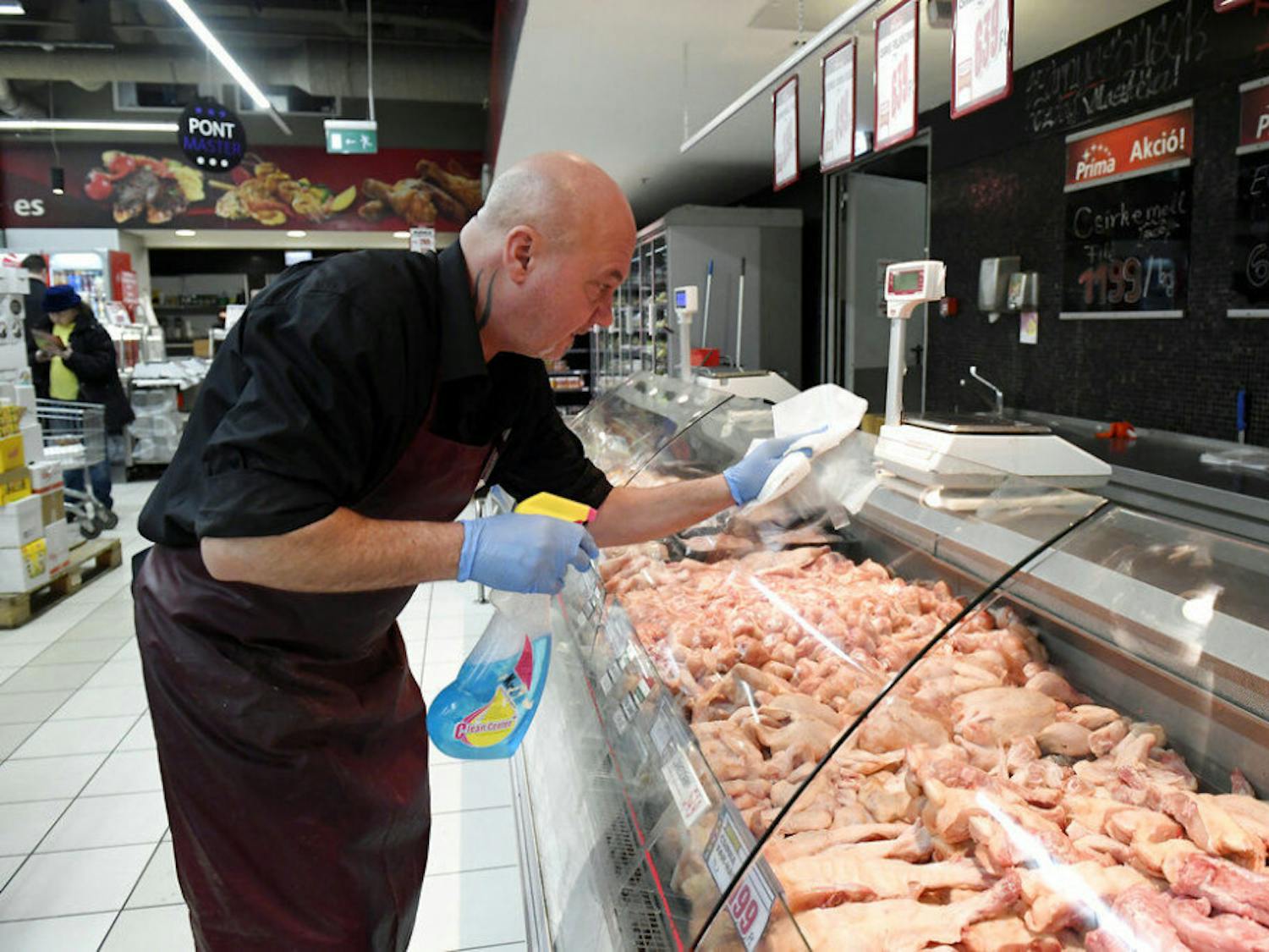 An employee disinfects the glass cover of a butcher counter to prevent the spread of the novel coronavirus in a food store in Budapest, Hungary, Wednesday, March 11, 2020. For most people, the new coronavirus causes only mild or moderate symptoms, such as fever and cough. For some, especially older adults and people with existing health problems, it can cause more severe illness, including pneumonia. (Tamas Kovacs/MTI via AP)