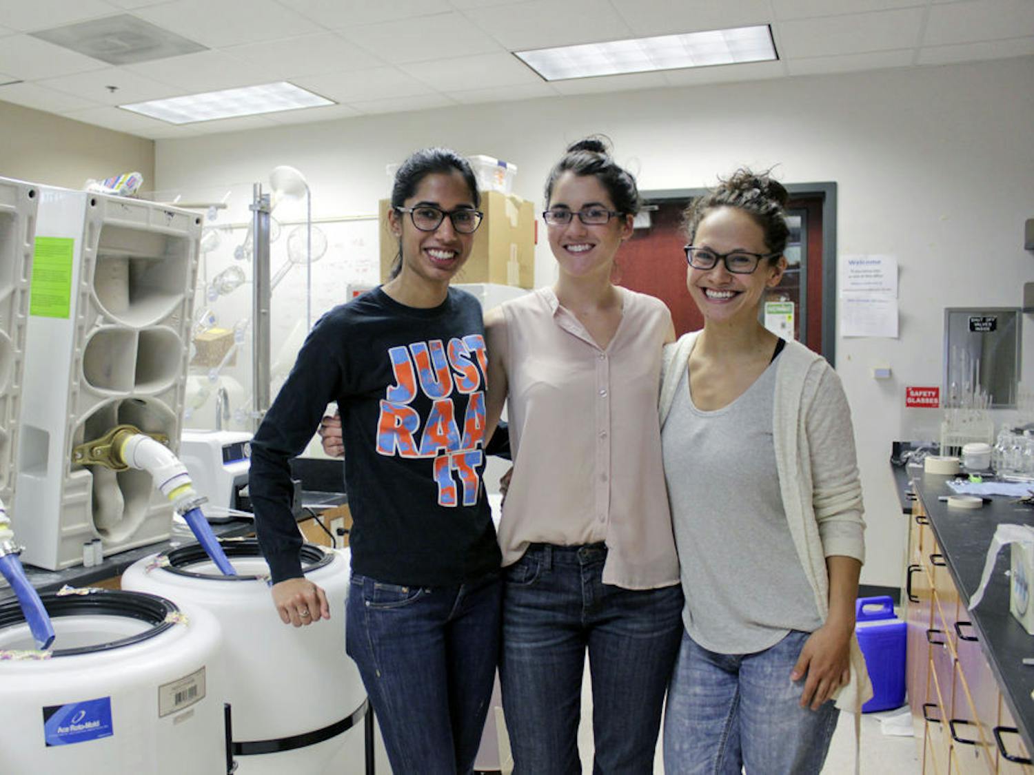 From left: Avni Solanki, 25, Kelly Landry, 27, and Stephanie Ishii, 27, all UF environmental engineering Ph.D. students, stand in a lab in the new engineering building next to urinals that they use to test part of the process they developed to purify human urine so it can be used to fertilize crops. They and the rest of their team will present their research in Alexandria, Virginia this weekend in hopes of winning more funding for the project.