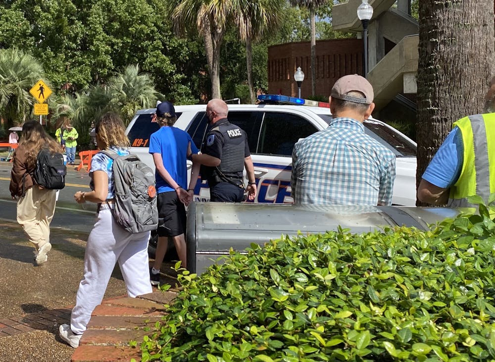<p>Joseph McDugald (middle), 18, UF freshman, is arrested by the University Police Department for refusing to leave an RTS bus in front of the Marston Science Library on Monday, Oct. 26, 2021. He was booked at the Alachua County Jail and released on Tuesday afternoon.</p>