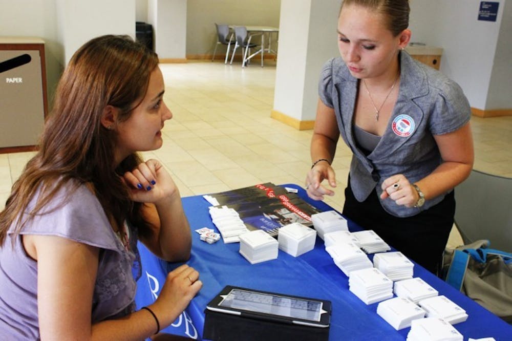 <p>Internal vice president of the Gator Coalition for Civic Engagement Kelly MacLellan, 21, assists Morgan Brown, 19, with the TurboVote program on a tablet.</p>