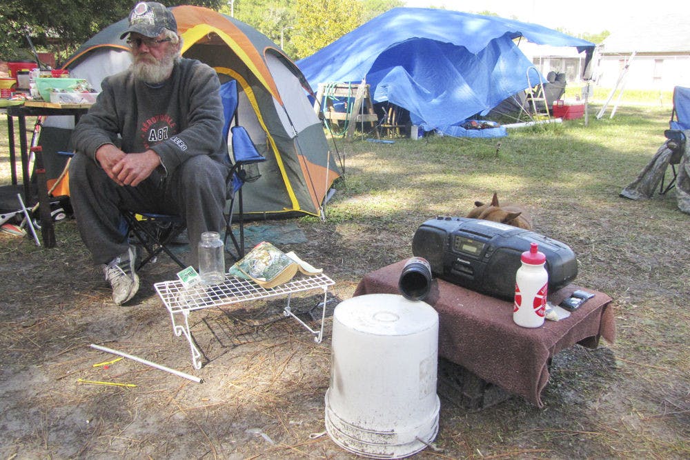 Russ Dye, 54, sits near his tent outside Grace Marketplace on Monday in four layers of clothes to shelter him from the cold. Dye said about 25 people at the shelter still need blankets and coats to bear the drop in temperatures.