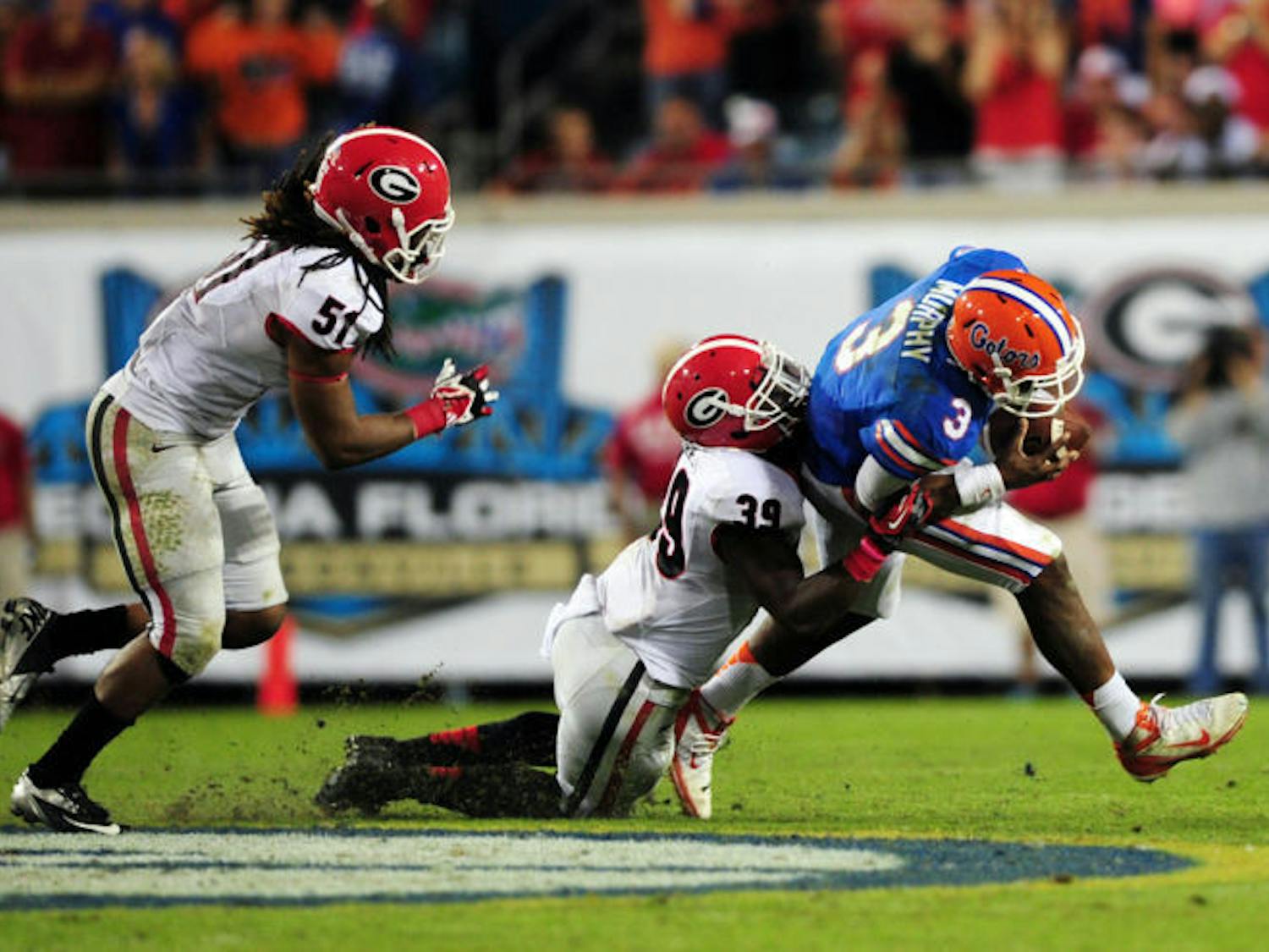 Georgia junior safety Corey Moore (39) tackles redshirt junior quarterback Tyler Murphy (3) during Florida’s 23-20 loss to the Bulldogs on Saturday at EverBank Field in Jacksonville.
