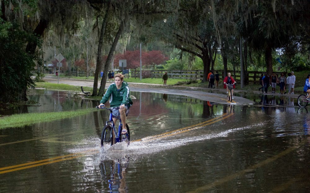 <p><span id="docs-internal-guid-845b8170-793b-be72-4928-eda85cab3022"><span>Students ride their bicycles through nearly a foot of water on the streets near Lake Alice. Lake Alice is one of the areas that flooded on campus during Hurricane Irma.</span></span></p>