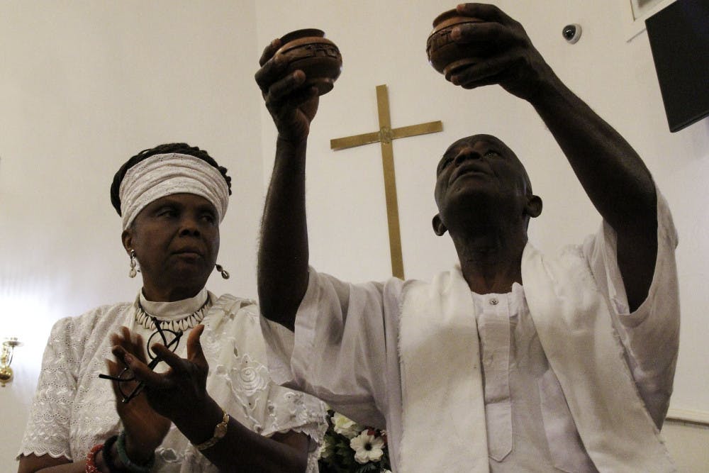 <p>D. Ayoka Sowa-La and her husband, Nii Sowa-La, perform a drum libation, a spiritual ritual involving the pouring of drink as an offering to deities, during the Alachua County lynching memorial service at Mount Pleasant United Methodist Church Friday evening. </p>