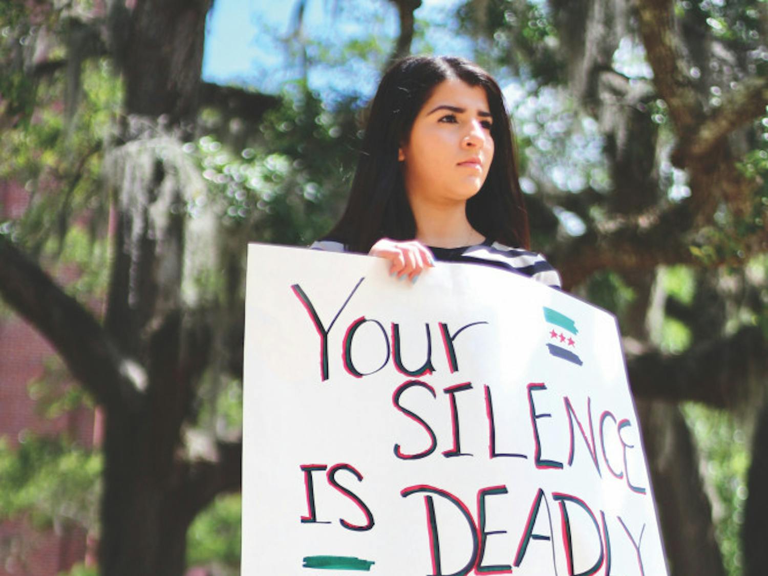 Rama Hussein, 21, a UF biology junior, holds a sign that reads "Your Silence is Deadly" while members of Students Organize for Syria demonstrated a die-in. 