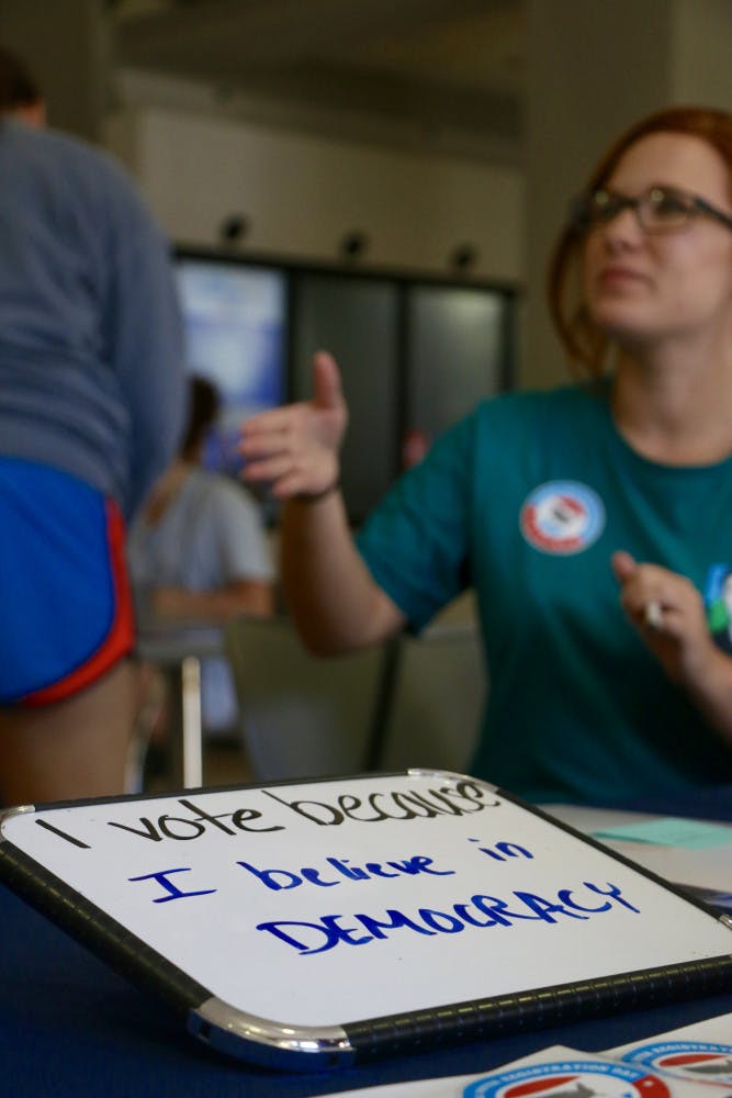 Megan Newsome, a 21-year-old UF astrophysics senior, gives instructions to other students in Pugh Hall as they register to vote. 