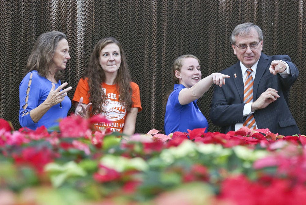 <p>From left to right, UF president’s wife Linda Moskeland Fuchs and 31-year-old UF agriculture and life sciences major Allison Bechtloff talk about the Environmental Horticulture Club while 22-year-old UF plant sciences junior Carly Anderson and UF President Kent Fuchs discuss the variety of poinsettias available at the greenhouse.</p>