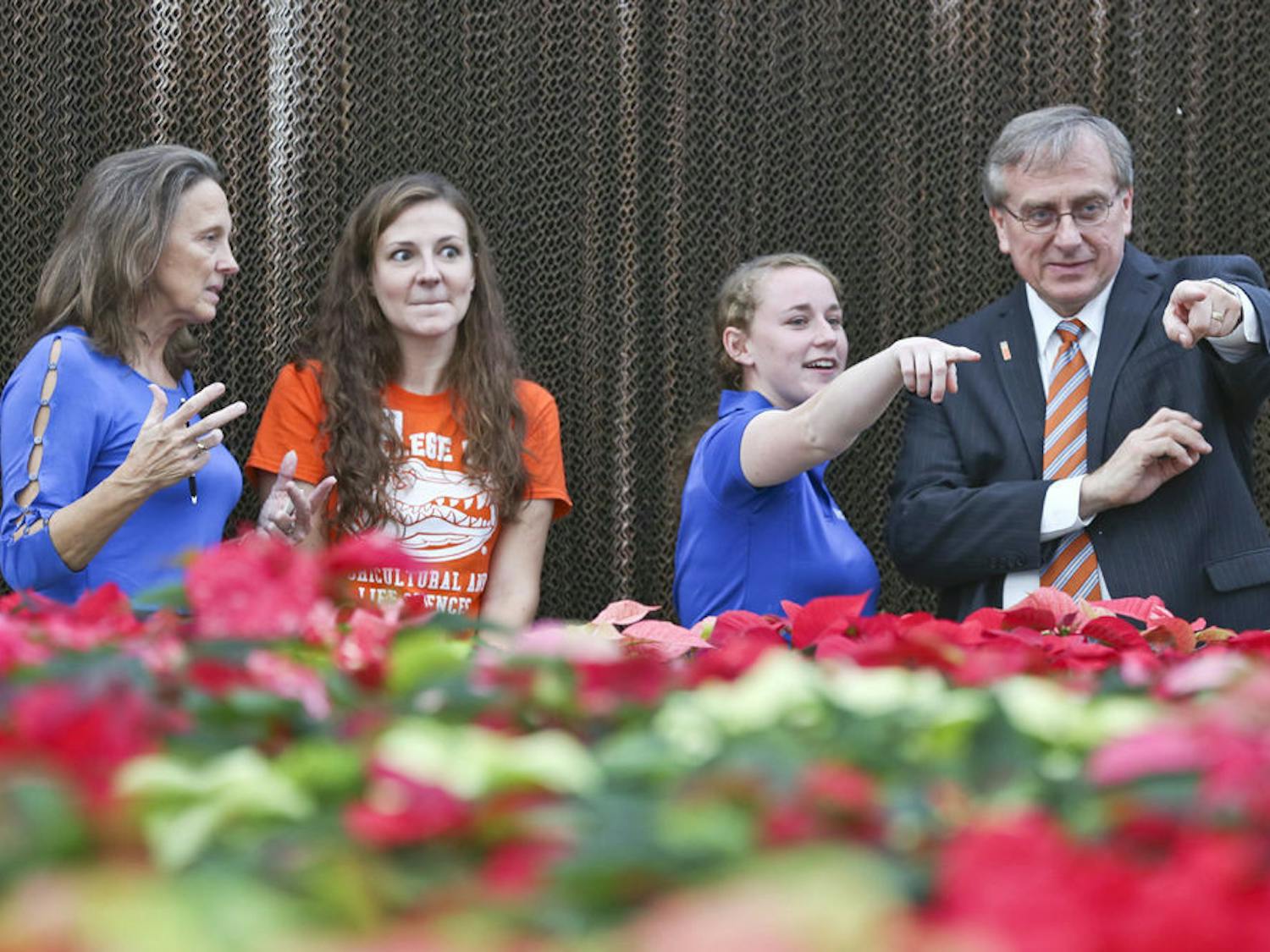 From left to right, UF president’s wife Linda Moskeland Fuchs and 31-year-old UF agriculture and life sciences major Allison Bechtloff talk about the Environmental Horticulture Club while 22-year-old UF plant sciences junior Carly Anderson and UF President Kent Fuchs discuss the variety of poinsettias available at the greenhouse.