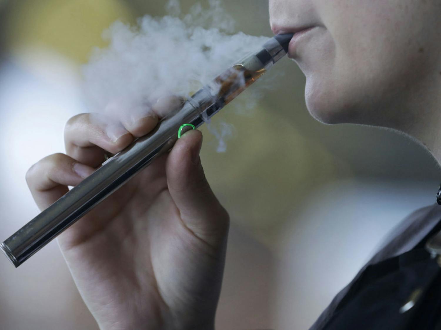 FILE - In this Friday, Oct. 4, 2019, file photo, a woman using an electronic cigarette exhales in Mayfield Heights, Ohio. A Michigan judge is blocking the state's two-week-old ban on flavored e-cigarettes. Court of Claims Judge Cynthia Stephens issued a preliminary injunction Tuesday, Oct. 15, 2019. She says Michigan Gov. Gretchen Whitmer's administration's delay in implementing the ban undercut its position that emergency rules were needed. (AP Photo/Tony Dejak, File)
