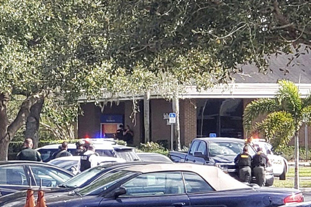 <p>Law enforcement officials take cover outside a SunTrust Bank branch, Wednesday, Jan. 23, 2019, in Sebring, Fla. Authorities say they've arrested a man who fired shots inside the Florida bank. (The News Sun via AP)</p>