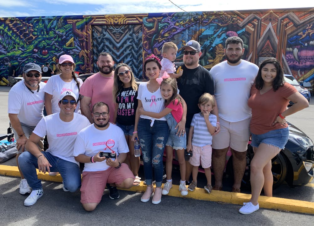 Michele Altomare (second from left) and Juan Reina (third from left), kneel on the ground as they pose with family and friends for a photograph during the third annual Breast Cancer Awareness Show in Tampa, Florida, where they raised awareness for cancer research on Sunday, October 13, 2019.

