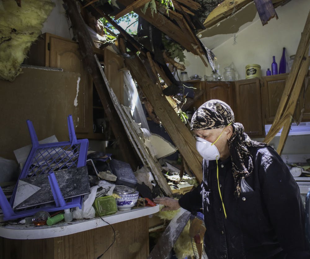 Alina Mitchell, 62, sorts through the debris in her kitchen after a tree crashed through the roof on Friday morning.