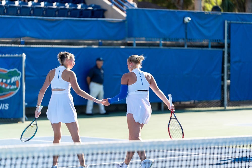 Florida women's tennis pairing of Alicia Dudeney and Malwina Rowinska high-five each other after a point in the team's match against Mississippi State on Friday, March 29, 2024. 