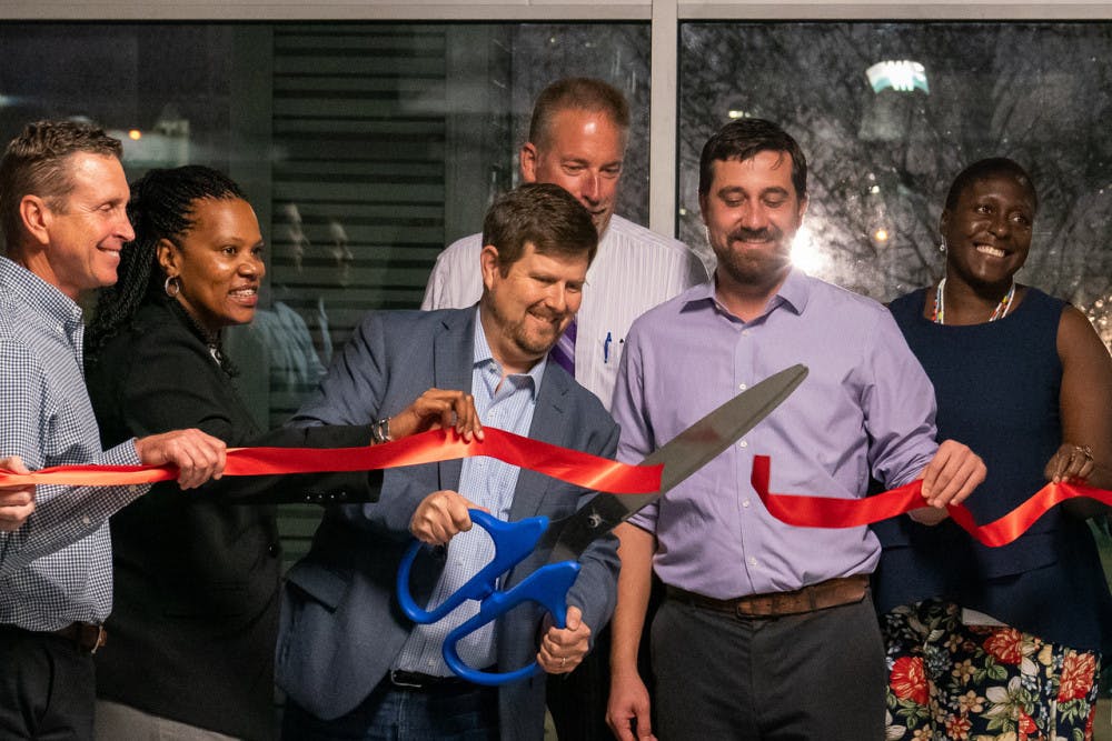 Gainesville Mayor Lauren Poe cuts a ribbon at a ceremony commemorating the completion of improvements to Southwest Sixth Street. He is joined by city commissioners and members of the planning team.