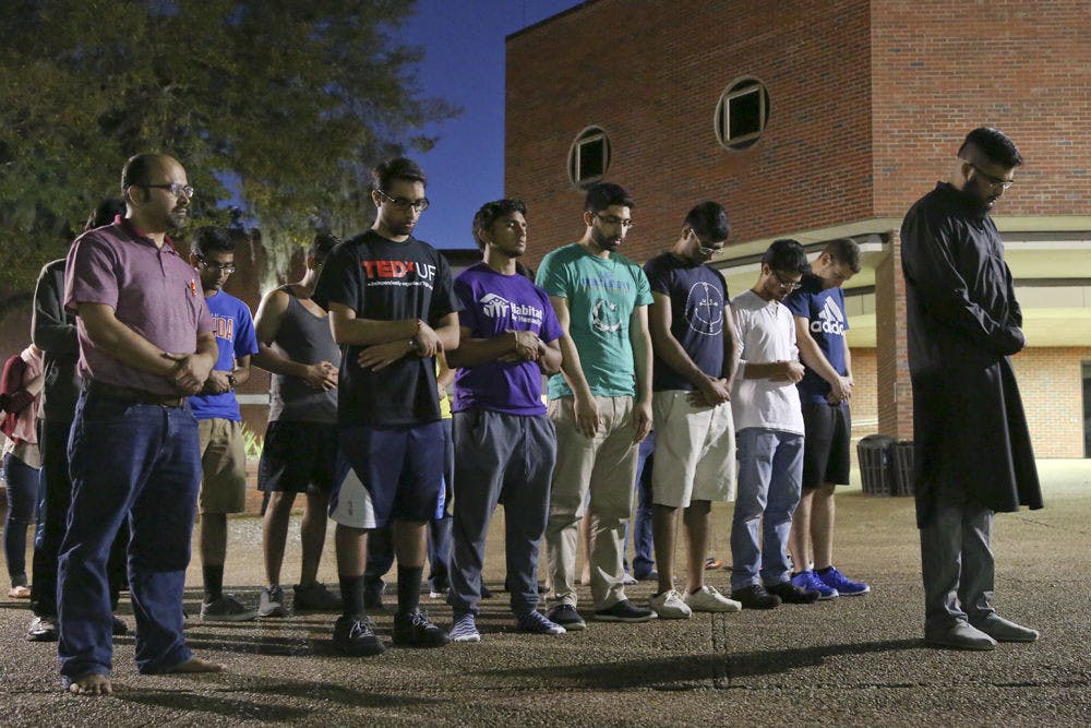 <p>Zubin Kapadia, a 21 year-old UF history senior, leads a group of Muslim UF community members in prayer honoring those killed during the terrorist attack in Pakistan on March 28. About 40 people attended the Monday night candlelight vigil on Turlington Plaza.</p>