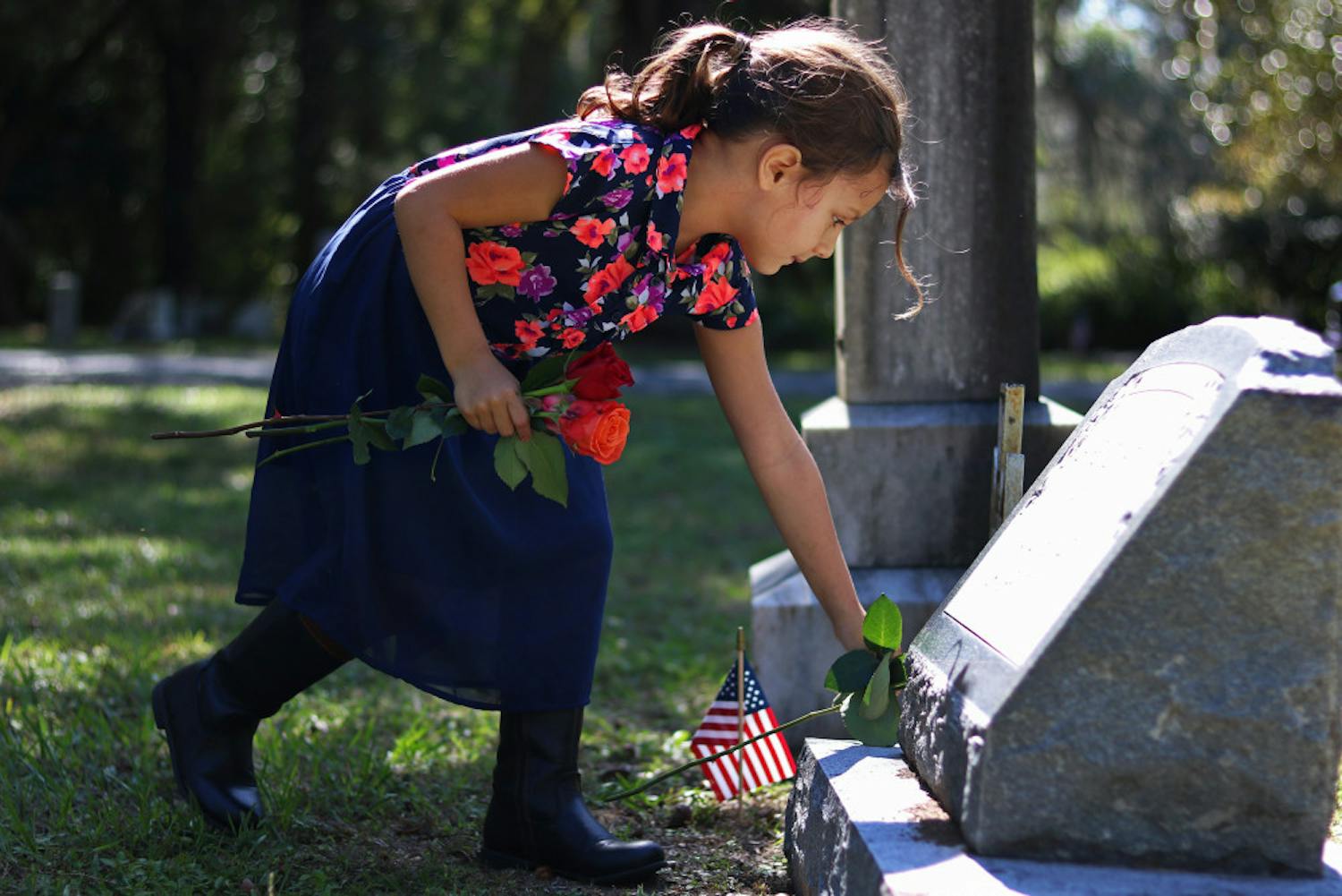 Svetlana Scalise, 6, places a flower on the grave of a veteran Monday in Evergreen Cemetery. Her father said she had the day off and wanted to spend it giving flowers to veterans.