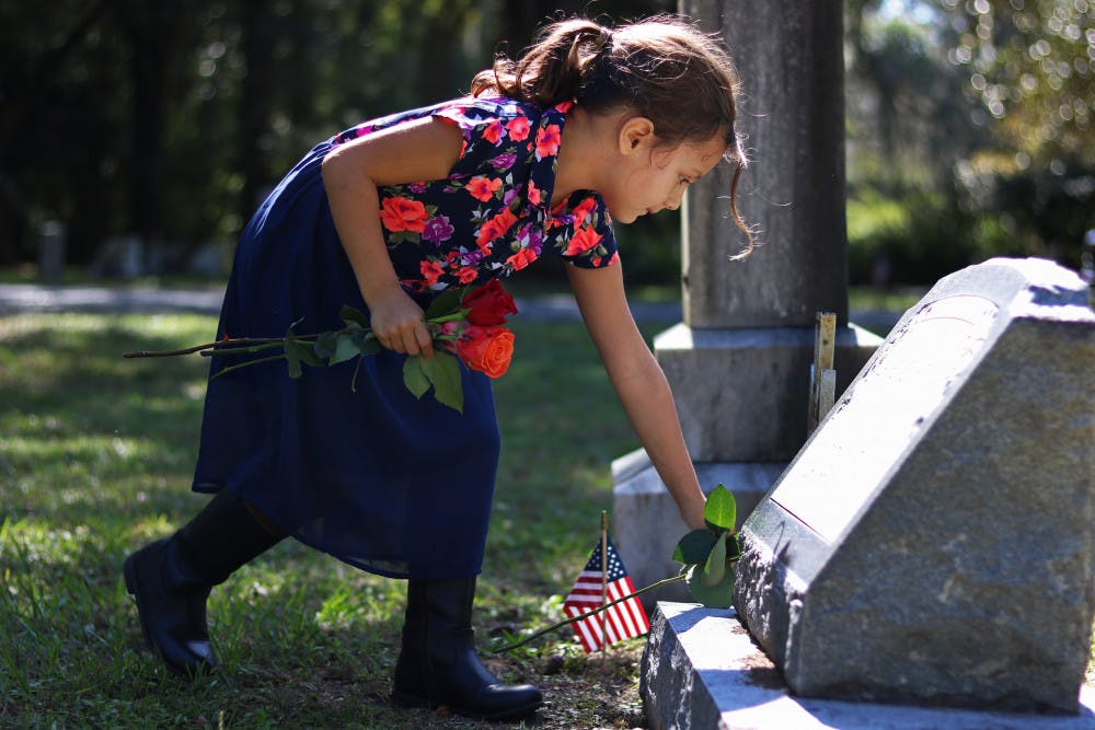 <p dir="ltr">Svetlana Scalise, 6, places a flower on the grave of a veteran Monday in Evergreen Cemetery. Her father said she had the day off and wanted to spend it giving flowers to veterans.</p>