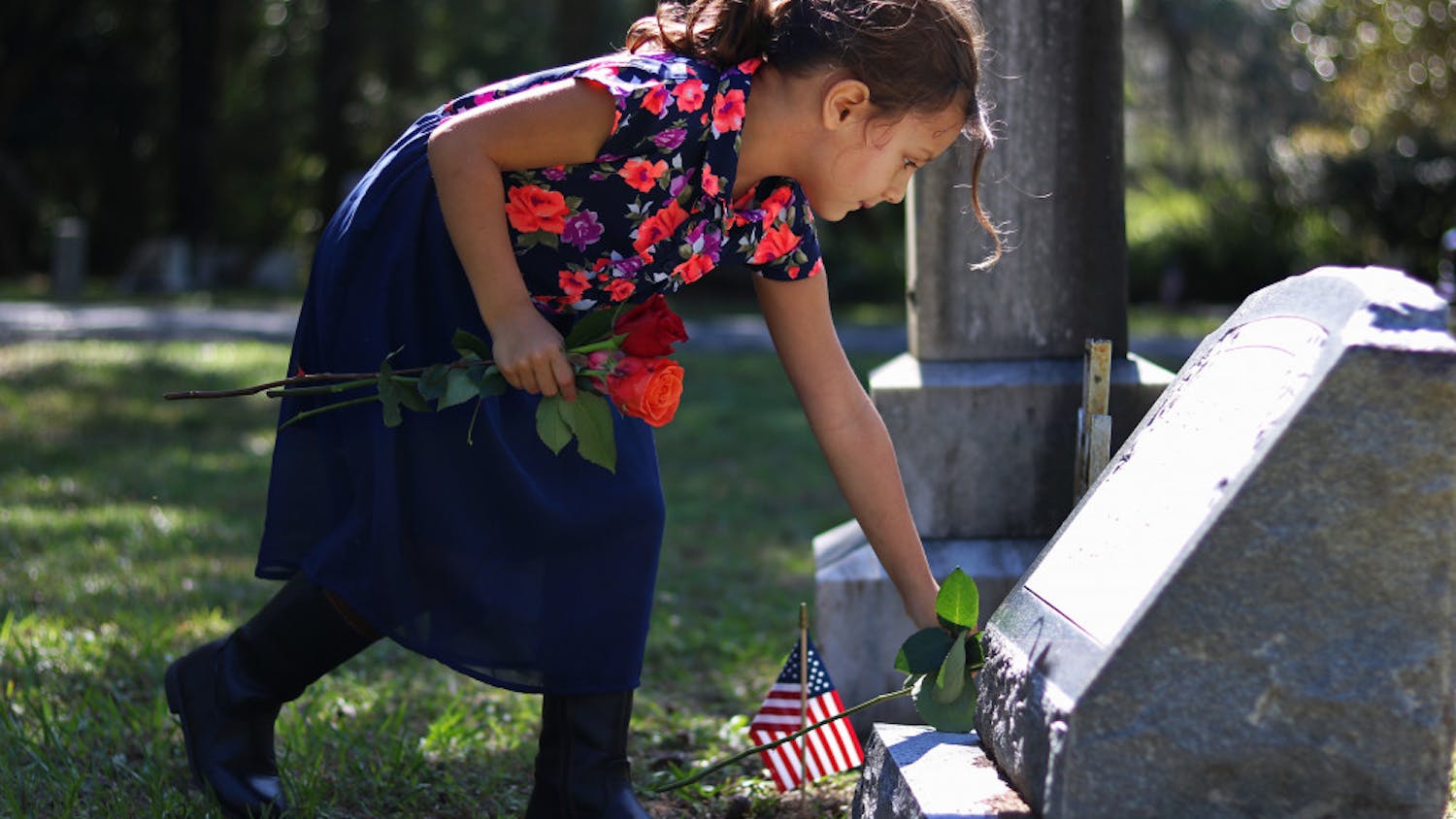Svetlana Scalise, 6, places a flower on the grave of a veteran Monday in Evergreen Cemetery. Her father said she had the day off and wanted to spend it giving flowers to veterans.