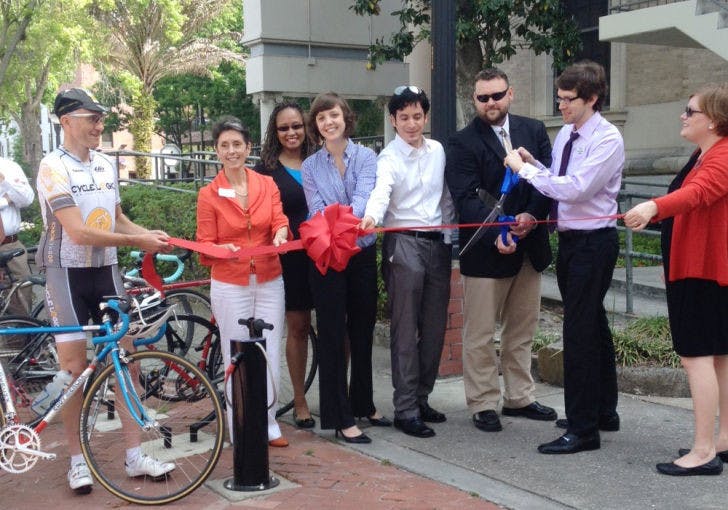 Commissioner Susan Bottcher, second from the left, and residents cut the ribbon at a “first pump” ceremony Monday morning. The event was held because the Alachua County Emerging Leaders, with the help of the City of Gainesville, installed new bike pumps downtown.&nbsp;