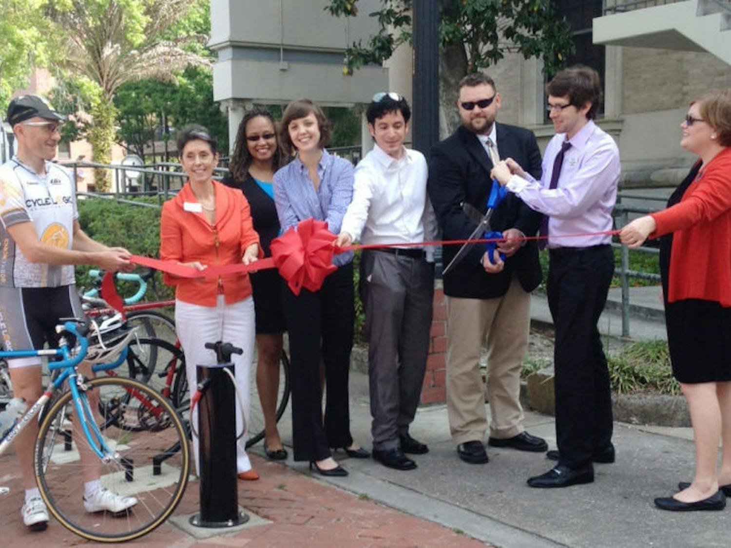 Commissioner Susan Bottcher, second from the left, and residents cut the ribbon at a “first pump” ceremony Monday morning. The event was held because the Alachua County Emerging Leaders, with the help of the City of Gainesville, installed new bike pumps downtown.&nbsp;