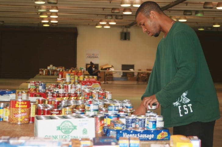 Odori Hines, a 31-year-old UF alumnus, sorts food collected Monday during the Strike Out Hunger Food Drive at the Alachua County Fairgrounds. “It’s actually a lot of fun,” he said.