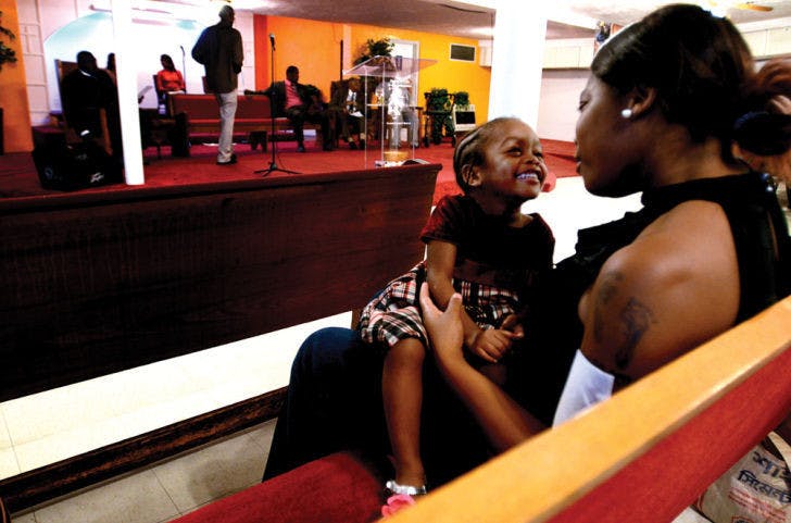 Bessie Collins, 22, sits with her 2-year-old daughter Dayla Jones at the dedication service Sunday afternoon. “I was surprised to see that the plaque was already up,” Collins said. “I had no idea that this building was a part of history until Pastor Duncan told us.”