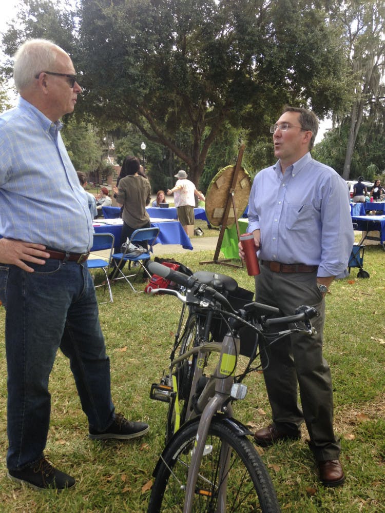 Former UF President Bernie Machen (left) converses with Matthew Williams, UF Office of Sustainability &amp; Energy Integration director, about his electric bike at the Sustainable Transportation Fair on the Reitz Union Lawn on Oct. 21, 2015. Williams said e-biking is "the fastest, easiest and most pleasant way to get around campus."