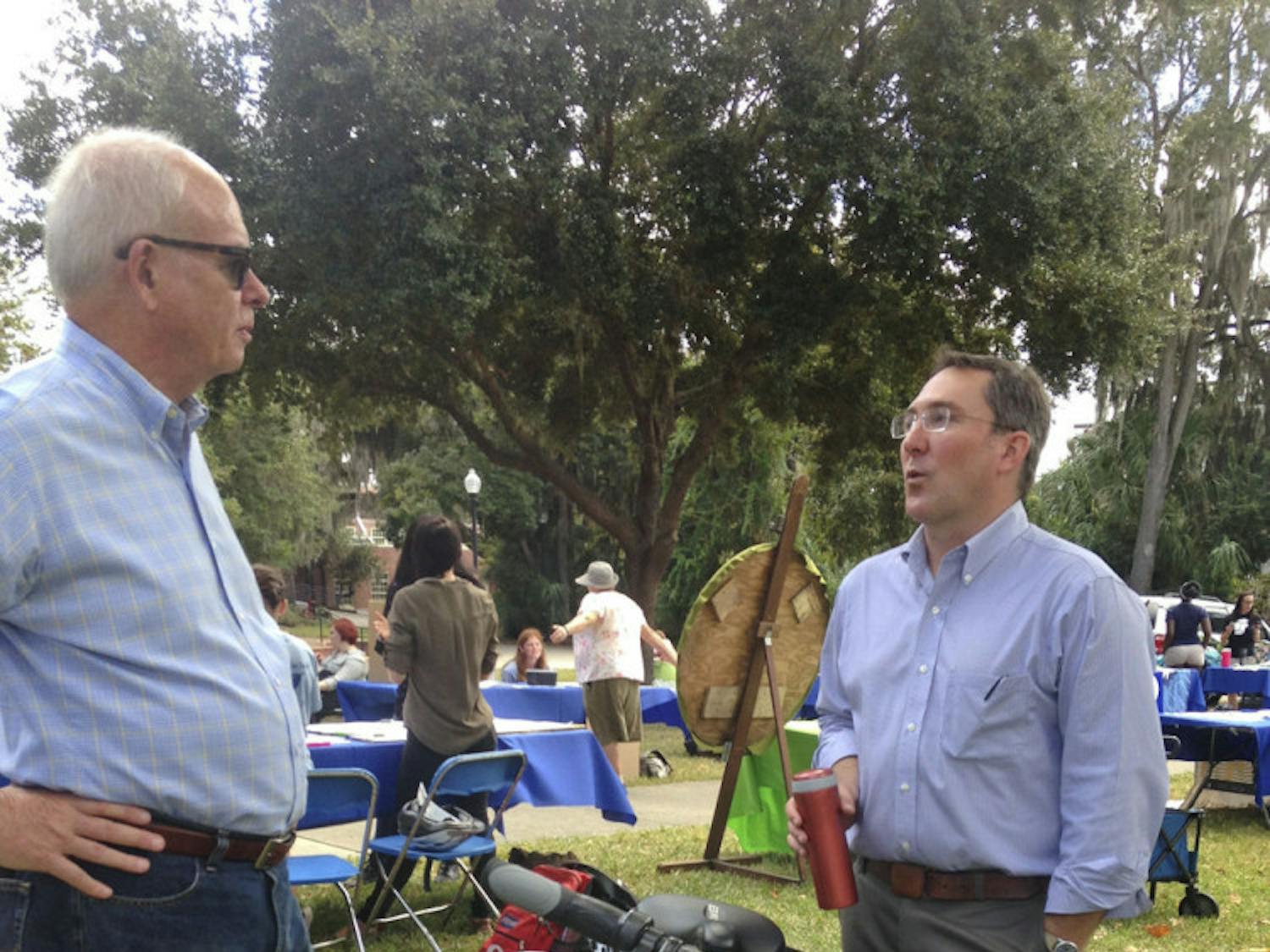 Former UF President Bernie Machen (left) converses with Matthew Williams, UF Office of Sustainability &amp; Energy Integration director, about his electric bike at the Sustainable Transportation Fair on the Reitz Union Lawn on Oct. 21, 2015. Williams said e-biking is "the fastest, easiest and most pleasant way to get around campus."