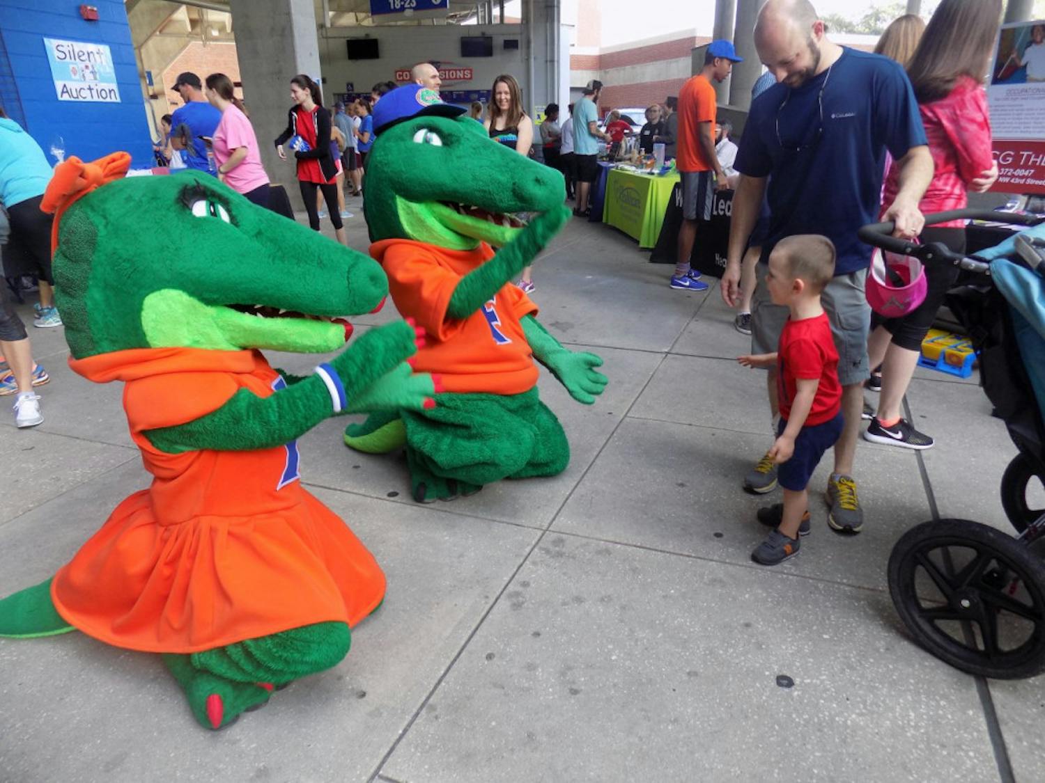 Albert and Alberta show their Gator spirit by chomping and playing with a child before attendees started to run laps around Ben Hill Griffin Stadium.