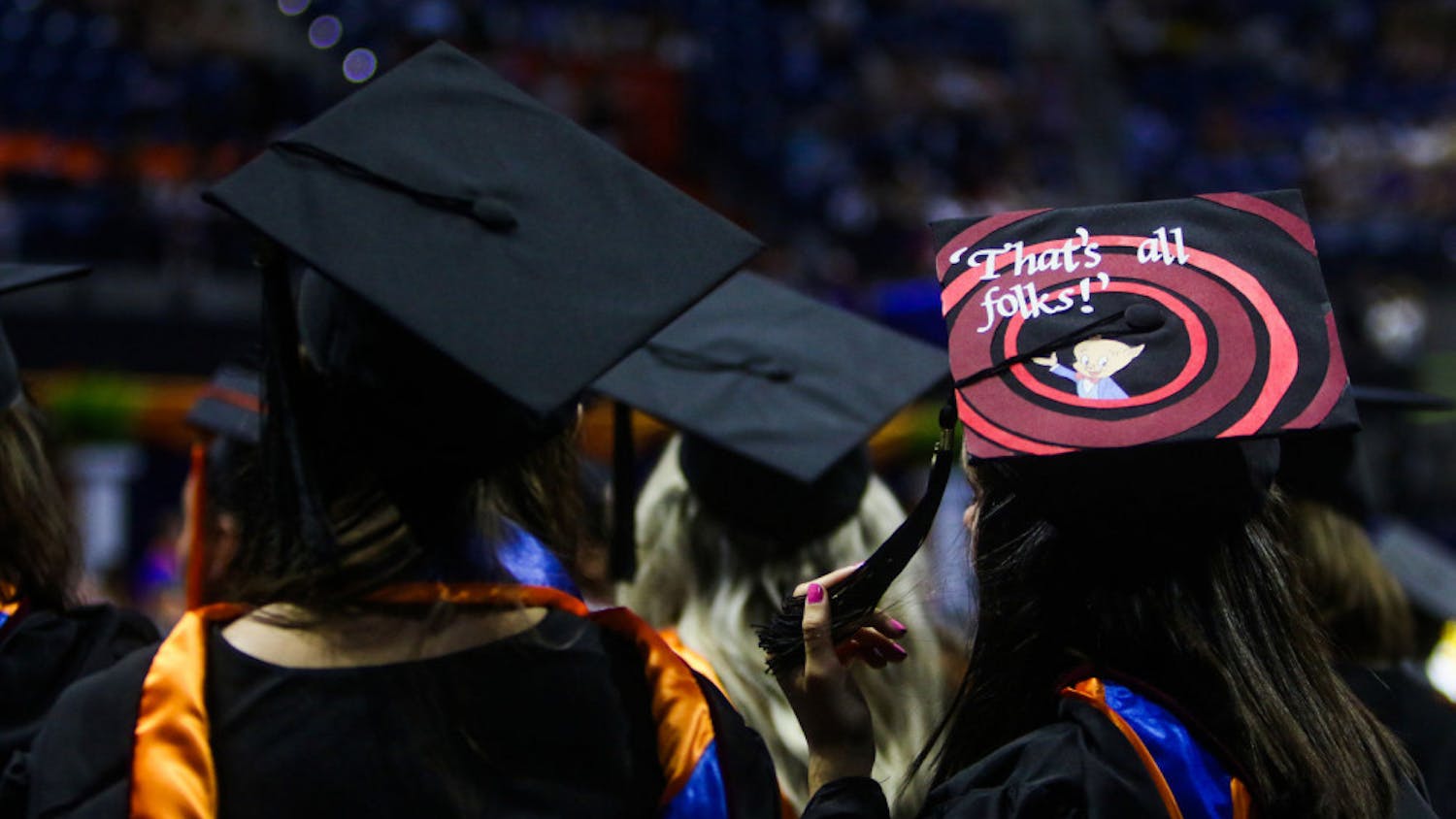 A Summer 2019 graduate of the University of Florida watches the remainder of the ceremony while wearing a graduation cap with the Porky Pig quote, “That’s all, folks,” from Looney Tunes.