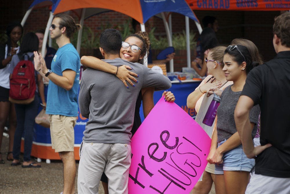 <p>Aleena Martin (right), a 19-year-old UF family youth and community sciences sophomore, gives a “Free Hug” to Tanuj Amalean, a 19-year-old UF mechanical engineering sophomore, in Turlington Plaza Sept. 8, 2015. Martin was with her Intro to Family, Youth and Community Sciences class giving free hugs as part of an extra-credit assignment. “We are encouraged to give healing through hugs,” she said.</p>