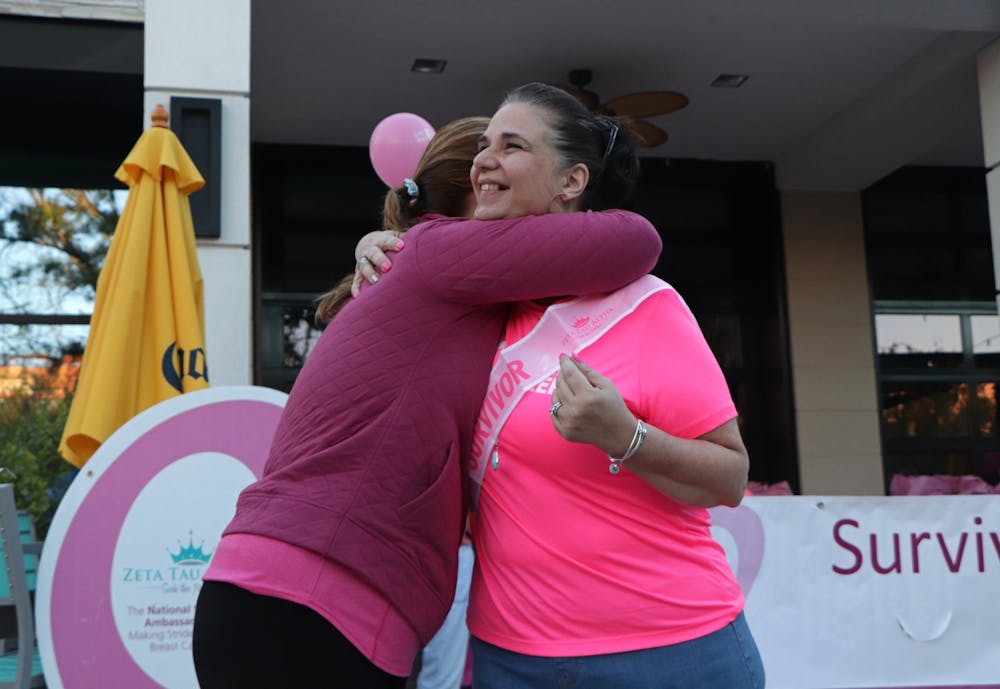 <p>Jennifer McKathan (left), American Cancer Society health systems manager, embraces Pam Clevenger (right) after she receives a breast cancer survivor sash at the Making Strides Against Breast Cancer event in Celebration Pointe on Saturday, Oct. 23, 2021. Clevenger, survivor for 12 years, is also a UF Health cancer patient navigator. </p>