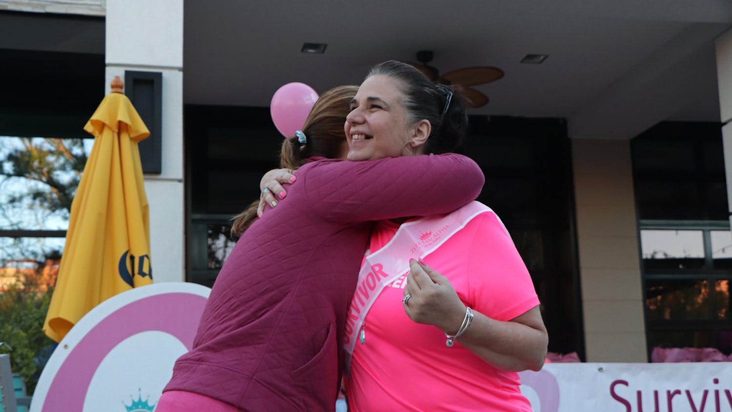 Jennifer McKathan (left), American Cancer Society health systems manager, embraces Pam Clevenger (right) after she receives a breast cancer survivor sash at the Making Strides Against Breast Cancer event in Celebration Pointe on Saturday, Oct. 23, 2021. Clevenger, survivor for 12 years, is also a UF Health cancer patient navigator. 
