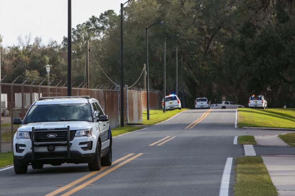 A University of Florida Police Department officer leaves the scene in a vehicle Friday while officers search a wooded area near the UF College of Veterinary Medicine for a suspect reportedly firing a gun at targets.